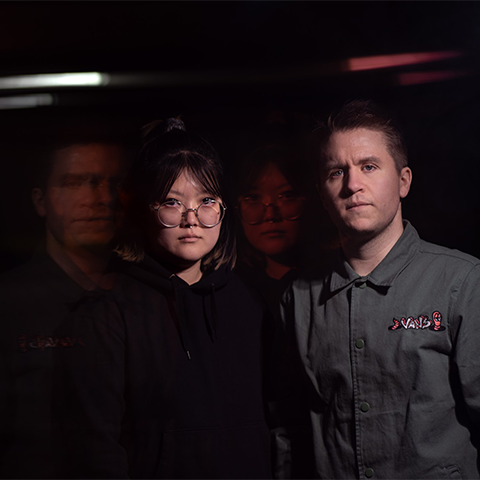 Duo members staring with a straight face with their silhoutte in the background