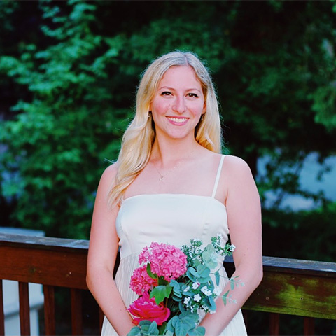 A woman in a white dress holds a bouquet of red flowers
