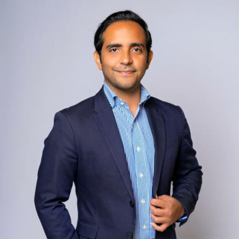 Carlos Vargas headshot: wearing a dark blue jacket and light blue button up.