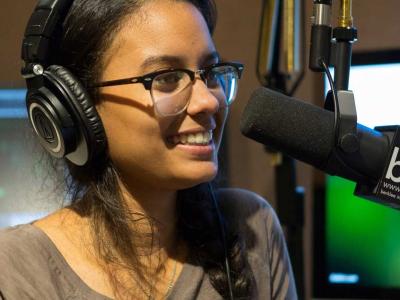 Smiling woman speaking into a microphone in a radio broadcasting studio