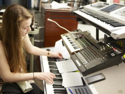 Young woman creating music with pianos and other professional electronic production equipment