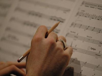 Close-up of hand holding a pencil over sheet music
