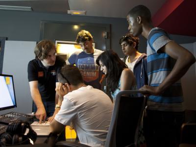 Group of young people learning how to use digital mixing equipment