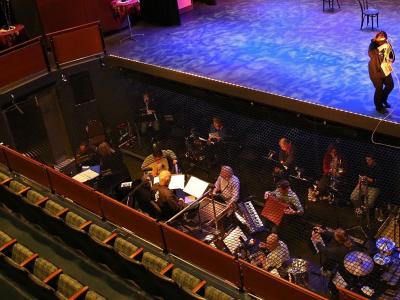 Aerial shot of an orchestra practicing in their area below the stage