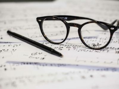 Glasses and pen resting on sheet music