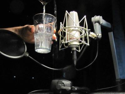 Person recording the sound of water filling up a glass
