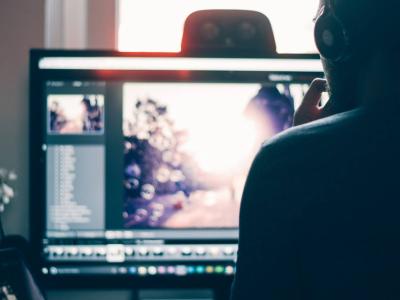 Person wearing headphones looking at video editing software on a laptop.