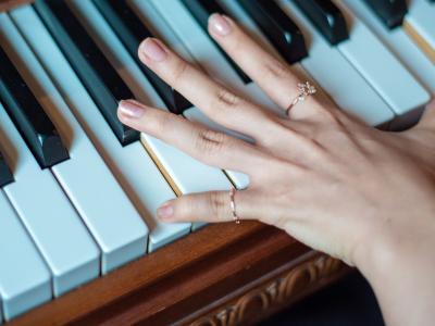 Hand wearing rings playing a piano chord