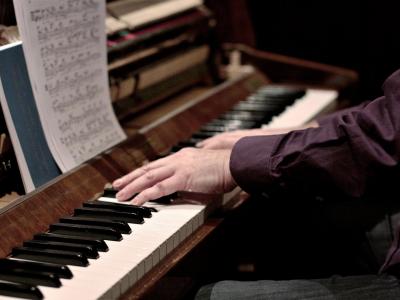 Person's hands on a piano with sheet music