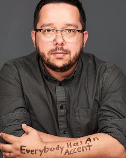 Headshot of Roberto with the writing "Everybody has an accent" on his forearm
