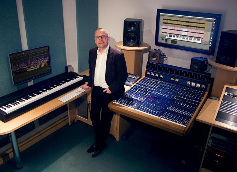 Joe Bennett standing in his music analysis studio 
