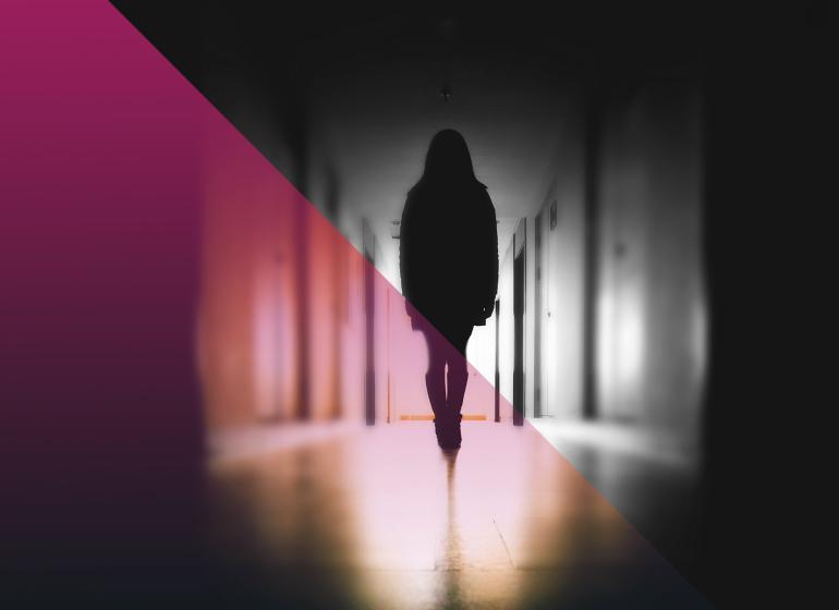 Black and white picture of a silhouette person in a school hallway with a pink hue on the left side 