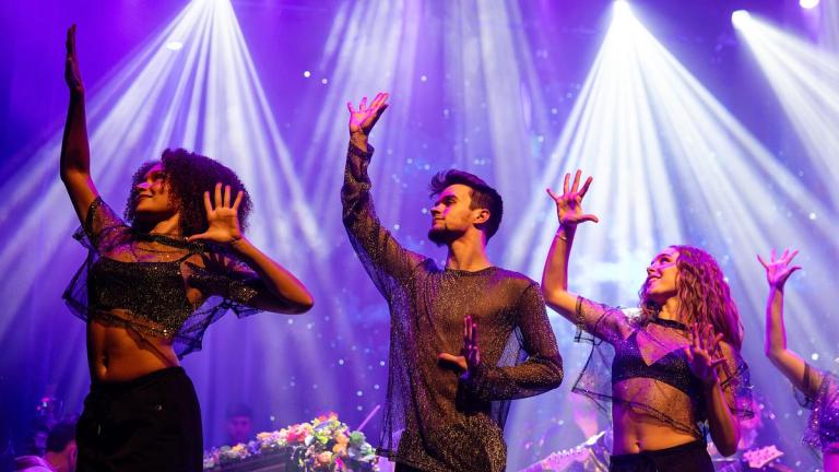 Students dancing on stage for the Coldplay Signature Series show with lots of spotlights in the background