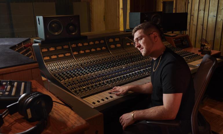 Charlie Rosen '12 behind a mixing board in a studio