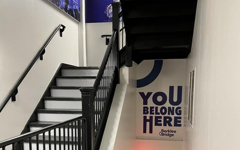 Stairwell featuring artistic text that says "You belong here" with the Berklee Bridge logo