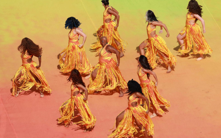 dancers dressed in yellow and orange perform in formation at FIFA world cup halftime show
