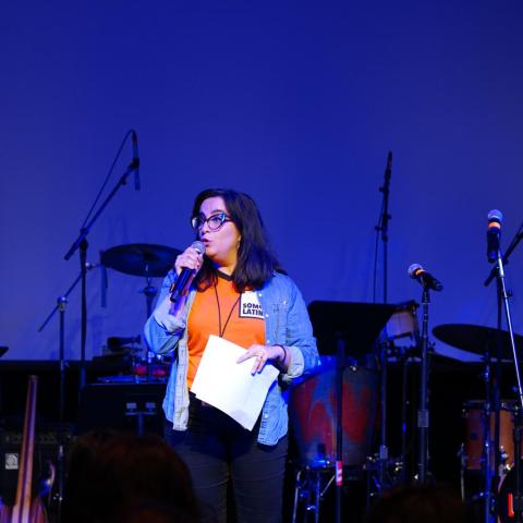 A woman, short dark hair, speaking into a microphone.