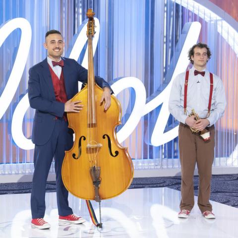 Colescott Rubin holds an acoustic bass on the American Idol audition stage alongside his brother A.J. who holds a trumpet.