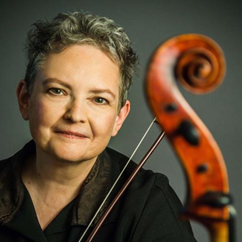 Rhonda Rider poses with her instrument against a grey blackground 