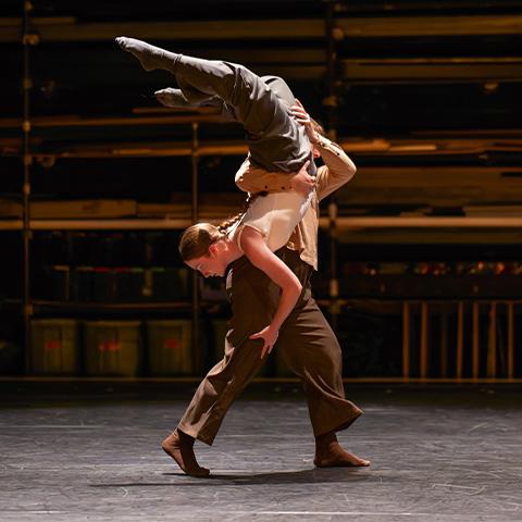 one dancer holding up another with legs in the air