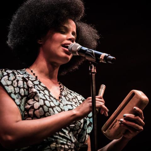 Melvis Santa sings at a microphone and plays claves