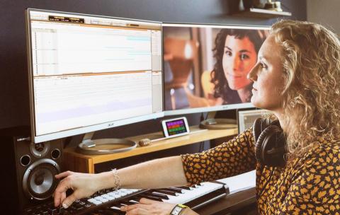 Woman composing to picture with her DAW and MIDI controller. 