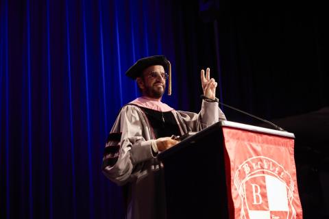Ringo Starr holding up a peace sign while wearing his honory doctorate robes 