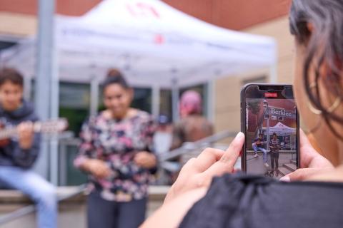 Student uses phone to film an outdoor performance 