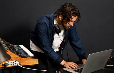 Man recording music with a laptop and key synthesizer