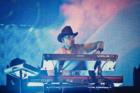 Rodney Alejandro performing in sunglasses and a cowboy hat playing keyboard