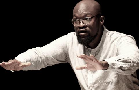 Vimbayi Kaziboni in a white shirt with arms stretched out as he conducts