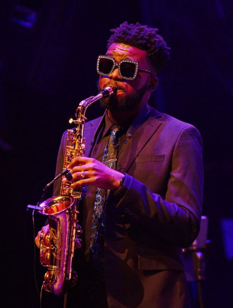 JahQuan Richards wearing sunglasses and playing alto saxophone on stage 