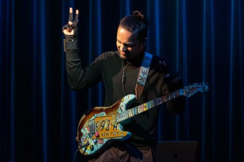 rishabh rajan playing a guitar while wearing a MIDI controller glove
