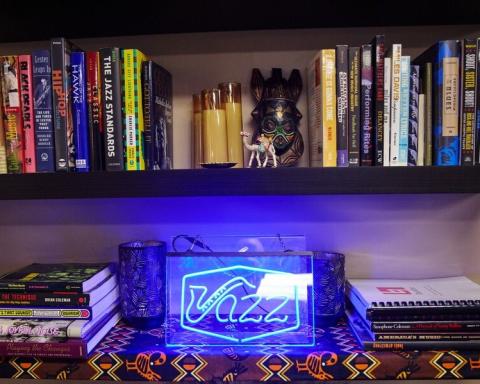 Photo of a shelf of records and books within the Africana Studies Center. A blue, neon sign spells out "Jazz."