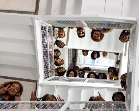 Photo from below, looking up at Africana Studies students posing in a stairwell from many different levels.