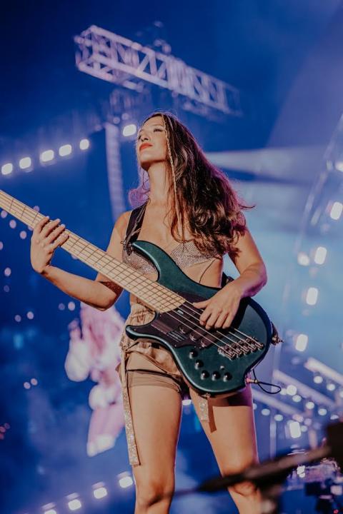 Patricia Ligia, Latina bass player and Berklee Alumni, playing a bass guitar at a concert.