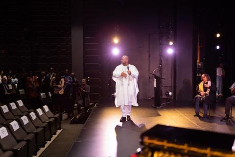 Dr. Emmett G. Price, III standing on the stage dressed in white African attire