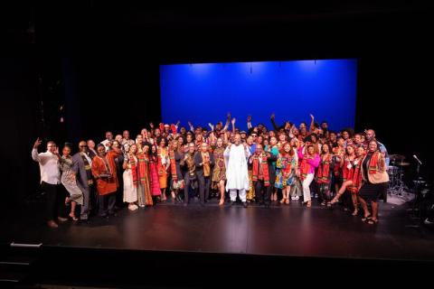 Group of African American students, faculty and staff posing for a group picture on the stage all dressed in African clothing