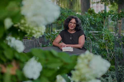 Lacretia Johnson Flash sits outside at a bistro table, surrounded by hydrangeas.