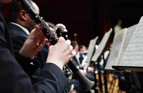 Photo from the side of a person playing the clarinet in an ensemble.