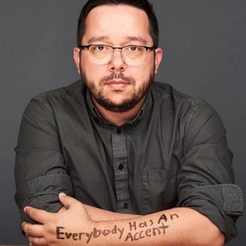 Headshot of Roberto with the writing "Everybody has an accent" on his forearm