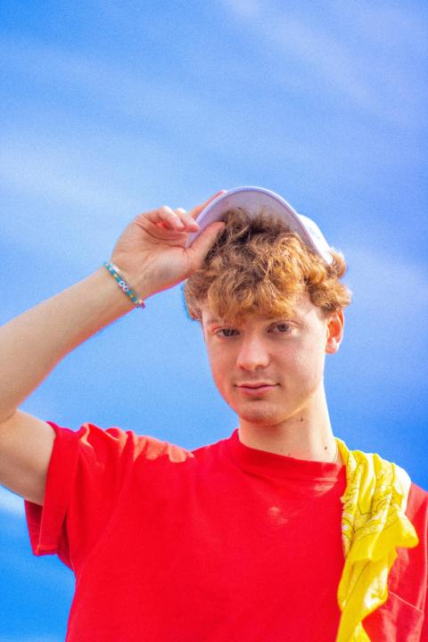 Keiran Rhodes headshot in a red tee shirt under a bright blue sky