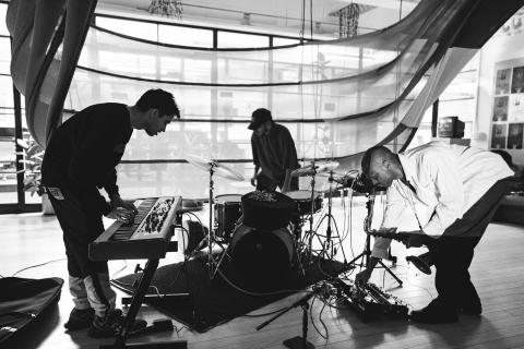 black and white image of a keyboardist, drummer, and saxophone player in a trio