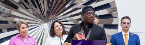 Poet Regie Gibson on stage behind a lectern holding a dictionary