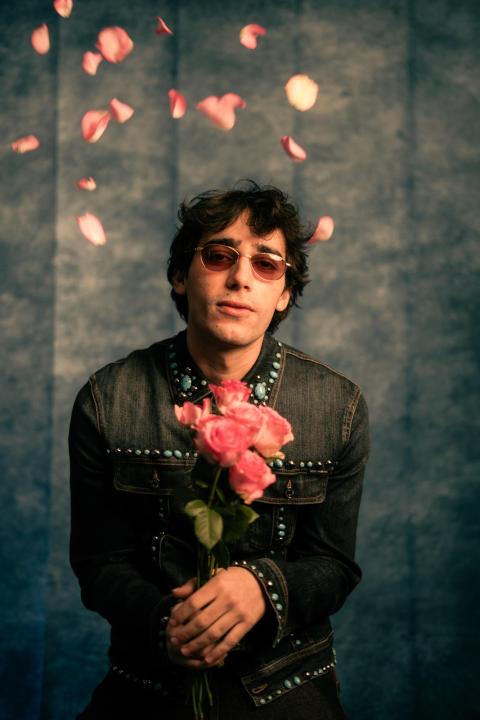 Beno against a stylized gray backdrop posing with flowers