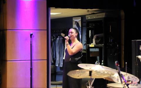 Woman in David Friend Recital Hall holding a mic with drums in the foreground