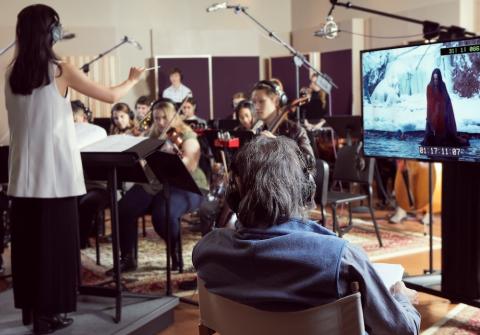 Student conducting a film scoring session in a Berklee recording studio.